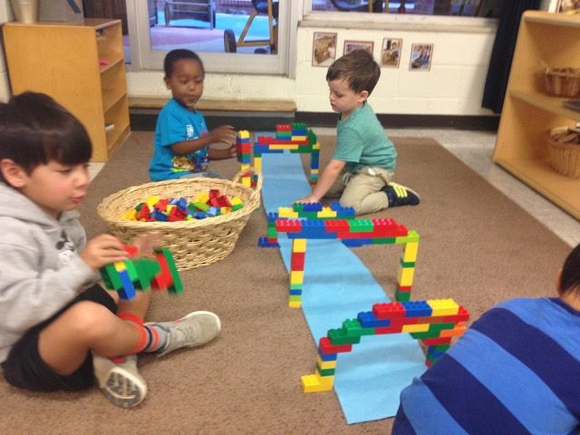 children playing with legos on the floor in a classroom