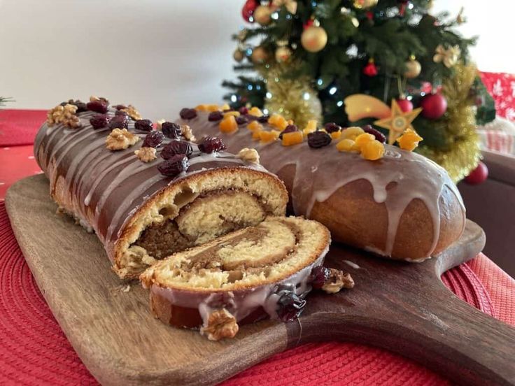 a loaf of cake sitting on top of a wooden cutting board next to a christmas tree