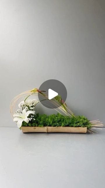 an arrangement of white flowers and greenery in a wooden box on a gray background