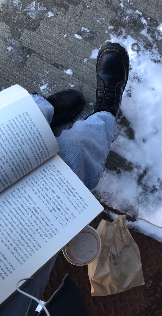 the person is reading a book outside in the snow