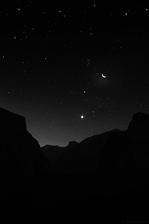 the night sky is filled with stars and moon in black and white, as well as mountains