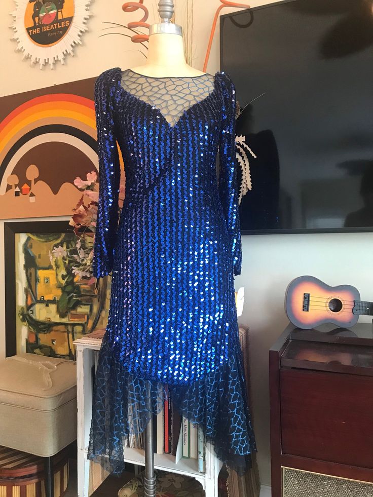 "Dramatic Royal Blue sequins with mosaic print mesh in the bodice and scarfed at the hem. Unique club dress or 80s party! 34\" bust 30\" waist 34\" hips 12-1/2\" side zipper 17-1/2\" from underarm to cuff hem 35\" from back of the collar to center hem 39\" from underarm to side mesh hem." Blue Sequin Dress Midi, Blue Embellished Sequin Fabric For Festive Occasions, Blue Sequin V-neck Dress, 80s Sequin Dress, 80s Blue Velvet Dress, Circle Skirt Dress, Amanda Dress, Sequined Dress, Club Dress