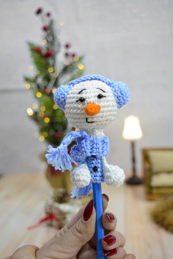 a crocheted snowman holding a blue toothbrush