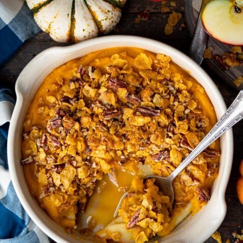 a bowl filled with food sitting on top of a table next to apples and pumpkins