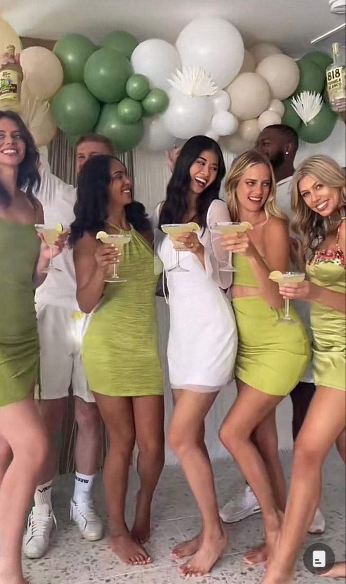 a group of women standing next to each other in front of balloons and holding drinks