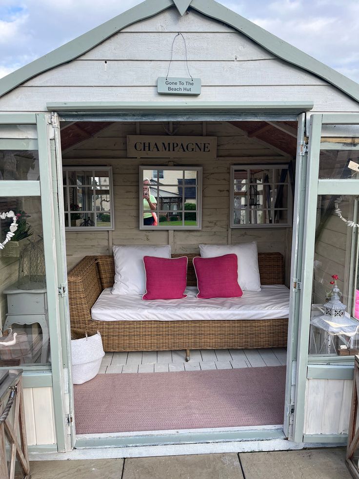 a bed sitting inside of a small wooden shed next to a window with pink pillows on it