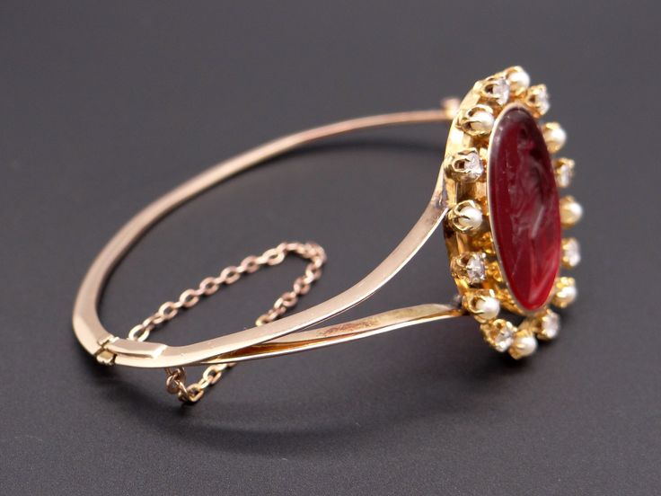 Jewelry Type: Bracelet Metal: 14k Yellow Gold Measurements: Length: 7 inch Top: 30mm x 25mm Markings: None ( scratch & acid tested) Weight: 17.2 grams Center: Oval Cut Venetian Glass w carved Intaglio Color: Red Measurements: 23mm x 18mm Accent Stones: 8 matching Rose Cut Diamonds Color: H Clarity: SI-1 Weight: 0.40cts total approx Accent Stones: 8 matching Round Pearls Color: White Measurements: 2.5mm #12219 Luxury Intaglio Jewelry For Evening, Fine Jewelry Bracelet With Cabochon, Elegant Oval Cabochon Cuff Bracelet, Yellow Gold Cabochon Bracelets For Weddings, Elegant Cabochon Cuff Bangle Bracelet, Luxury Cabochon Bangle Jewelry, Luxury Cabochon Bracelets For Wedding, Luxury Wedding Bracelet With Cabochon, Elegant Cabochon Bangle Jewelry