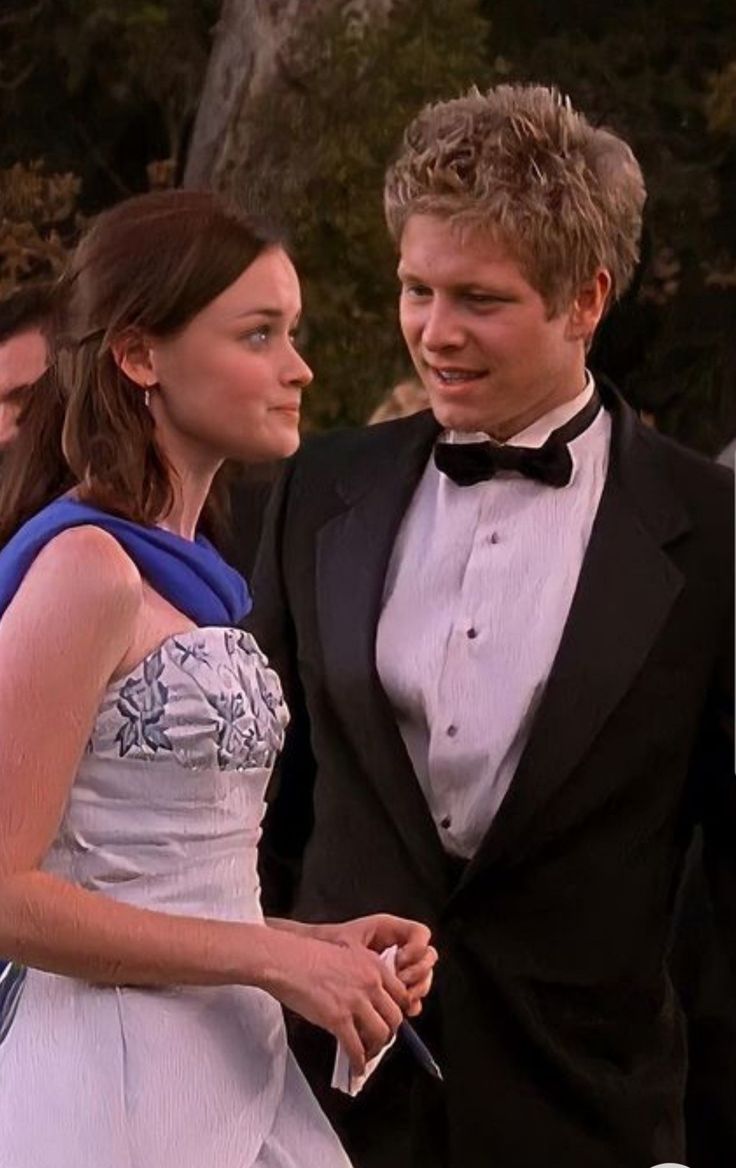 a man in a tuxedo standing next to a woman