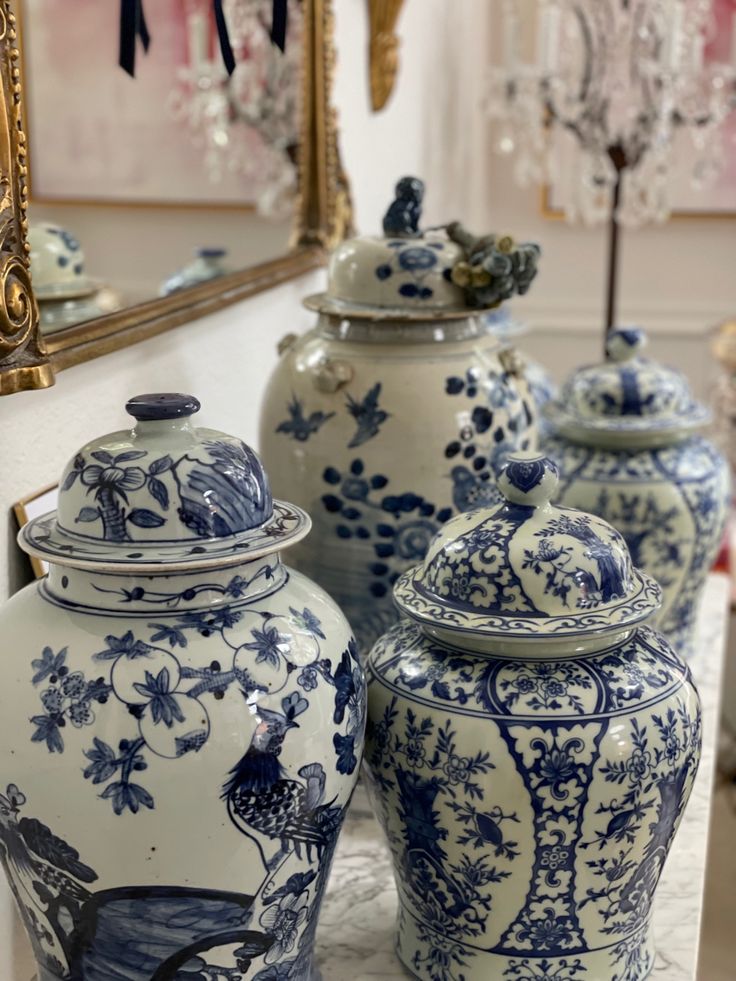 three blue and white vases sitting on top of a table next to a mirror