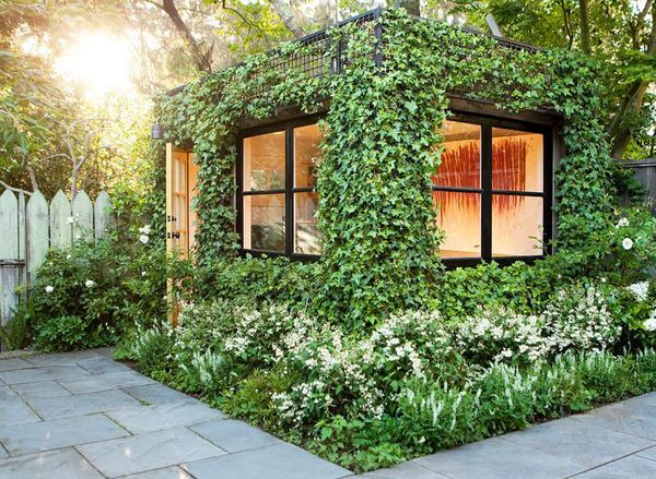 a house made out of plants and flowers in a backyard with a potted planter