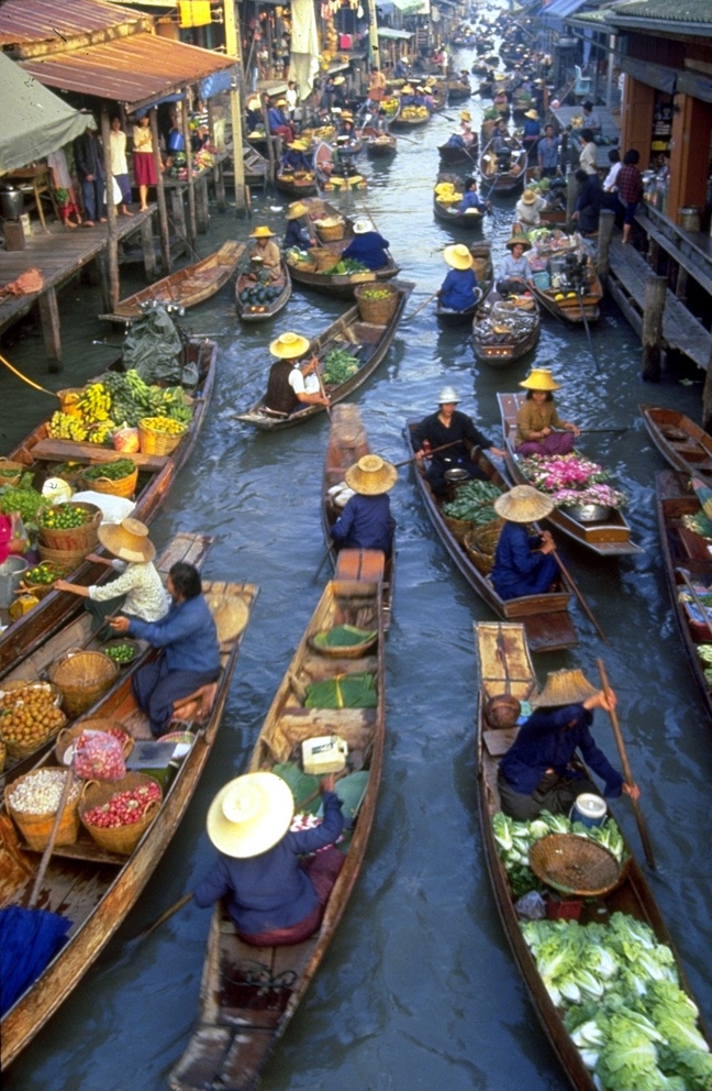 several boats filled with people and vegetables floating down a river