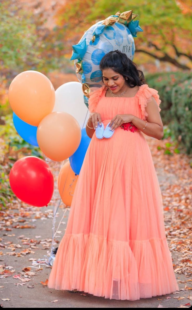 a woman in an orange dress holding balloons