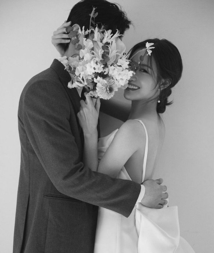 a bride and groom embracing each other in black and white photo with flowers on their forehead