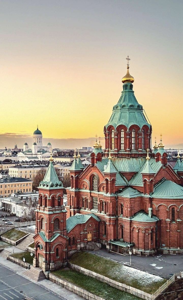 an aerial view of a large building with many spires and green roof tops at sunset