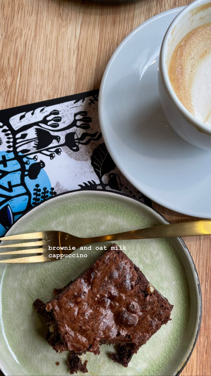 there is a piece of brownie on the plate next to a cup of coffee