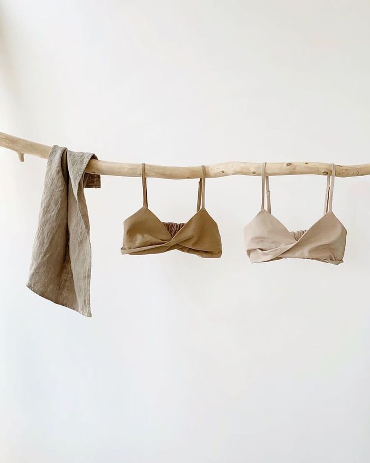 three bras hanging on a clothes line against a white wall, with one tied up and the other untied