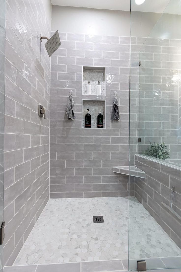 a walk in shower sitting next to a tiled wall