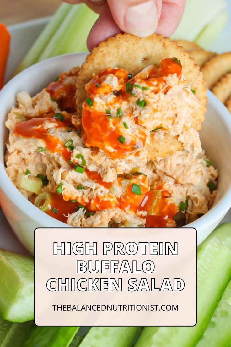 a bowl filled with chicken salad next to crackers and celery sticks on a white plate