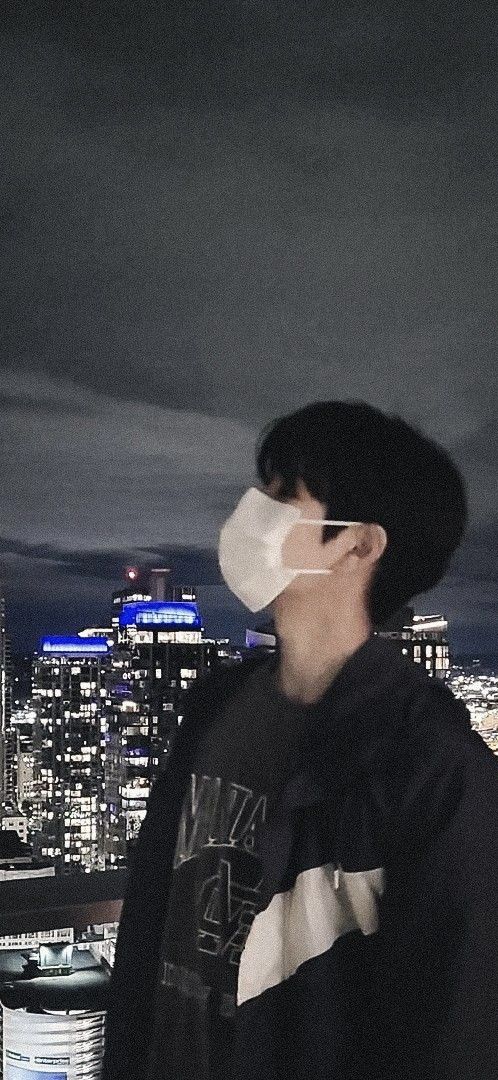 a man wearing a face mask standing in front of a cityscape