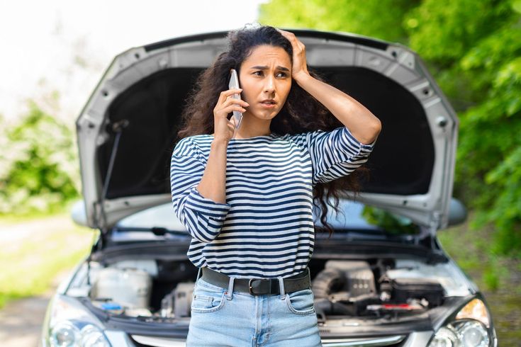 a woman holding a cell phone to her ear while standing in front of a car