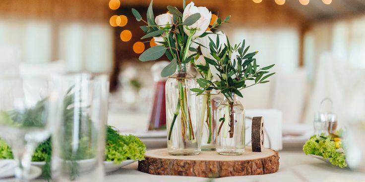 vases with flowers and greenery sit on a table at a wedding breakfasteon