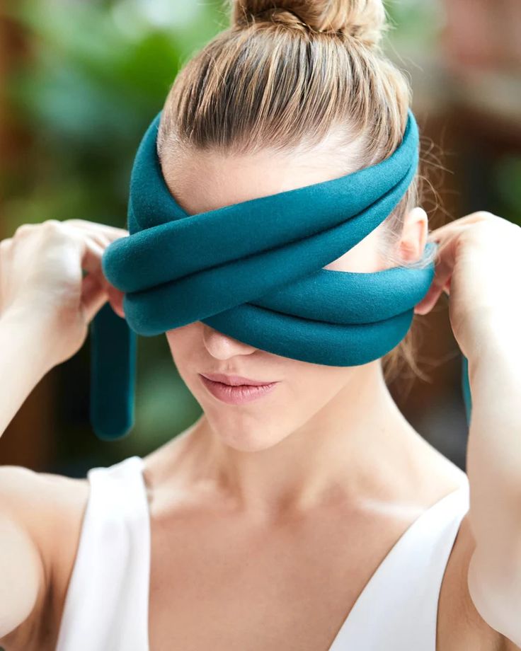 a woman is holding her head in front of her eyes as she covers her eyes with a piece of fabric