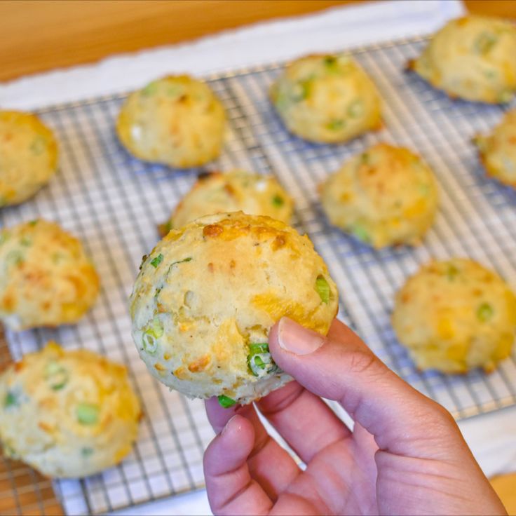 a person holding up a muffin in front of some other muffins