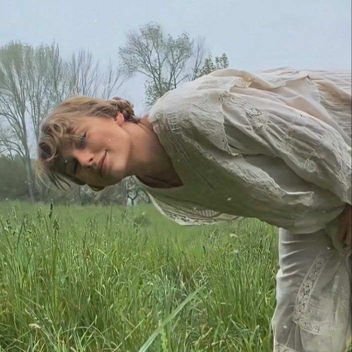 a woman bending over in the middle of a field