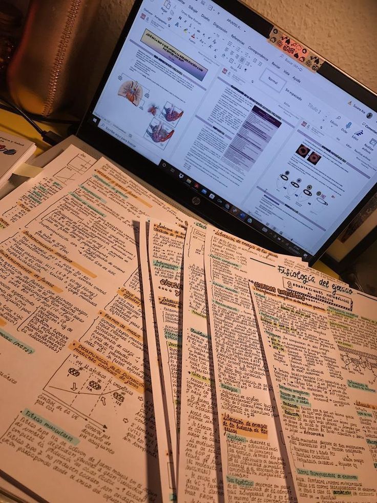 a laptop computer sitting on top of a desk covered in lots of paper work papers