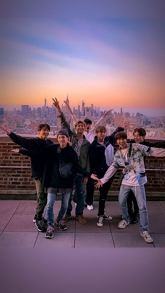 a group of young men standing next to each other on top of a tall building