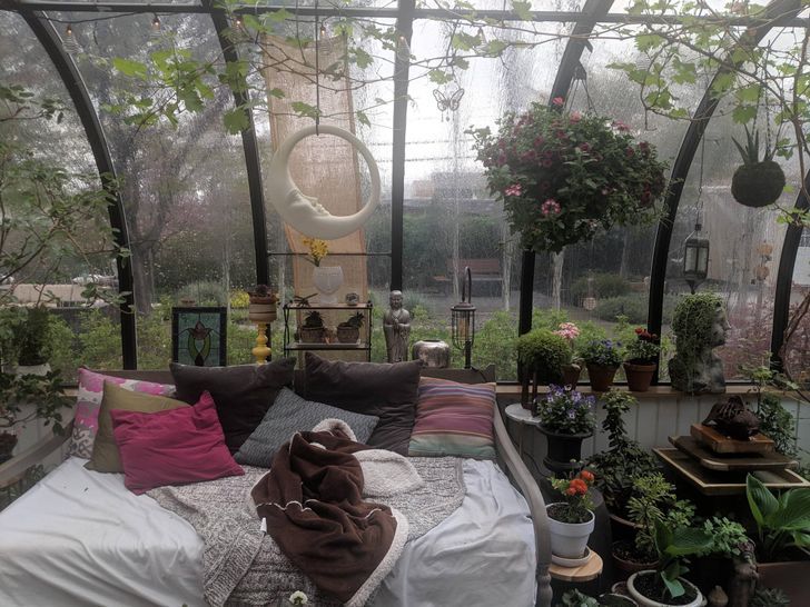 a bed sitting inside of a greenhouse filled with lots of plants and potted plants