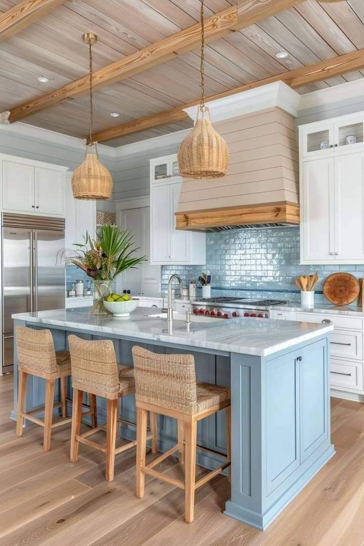 a kitchen with blue and white cabinets, wood floors and an island in the middle