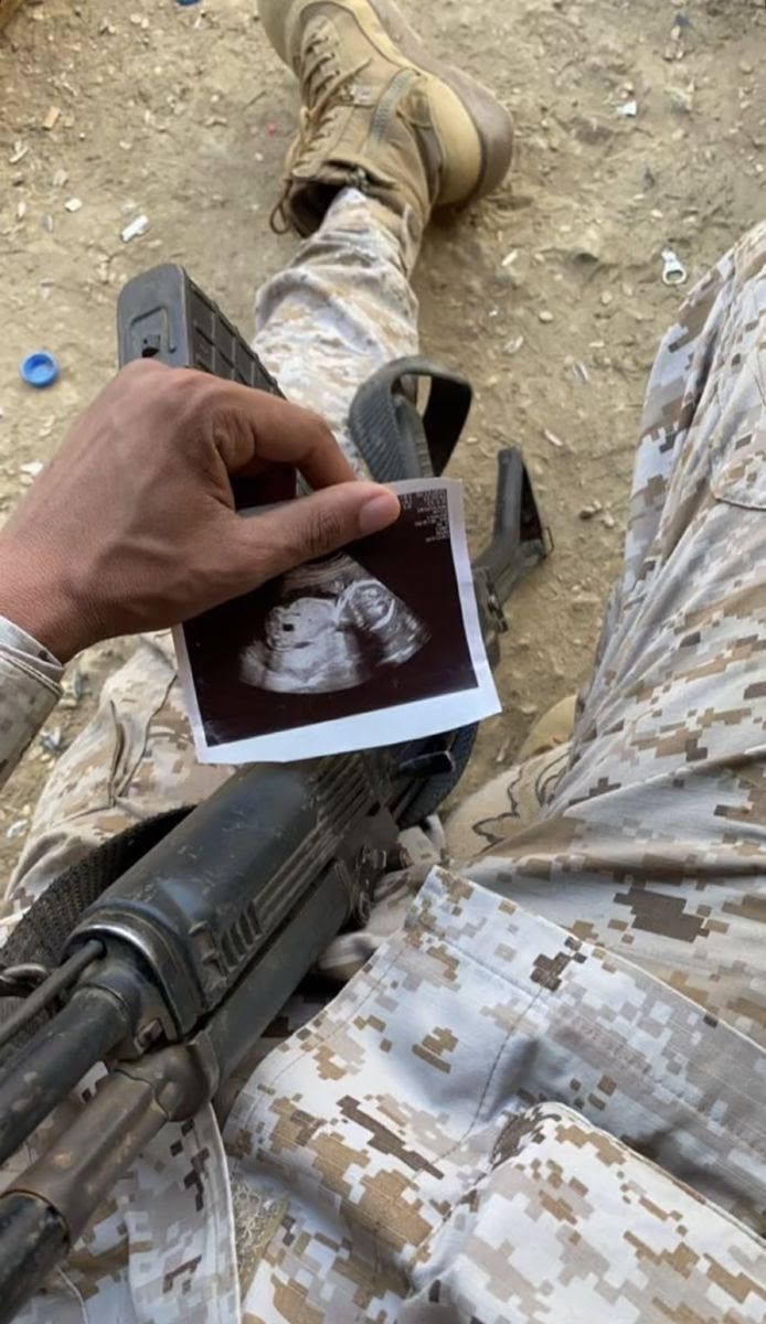 a soldier is holding a card with a picture of a man in the middle of his body