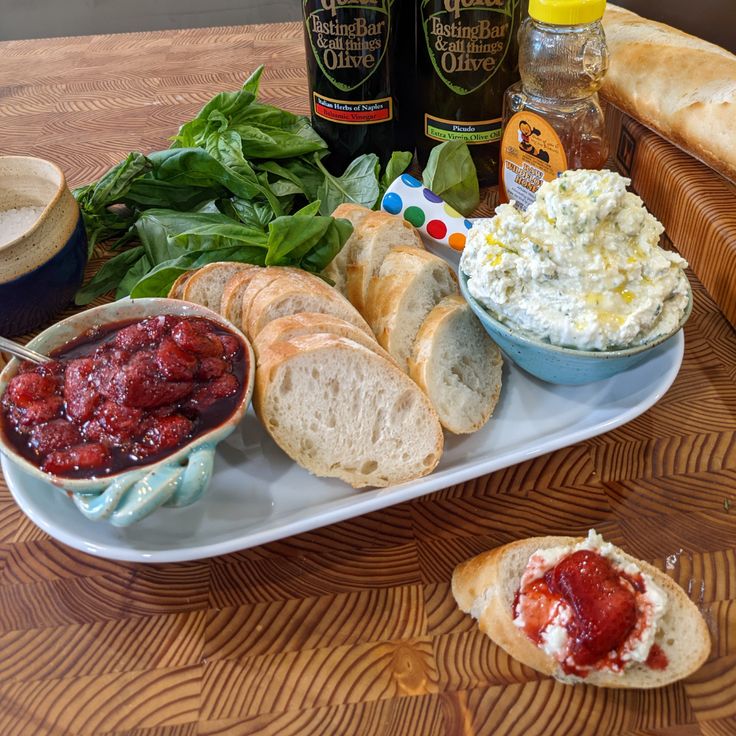 bread, dips and other food items on a white plate sitting on a wooden table