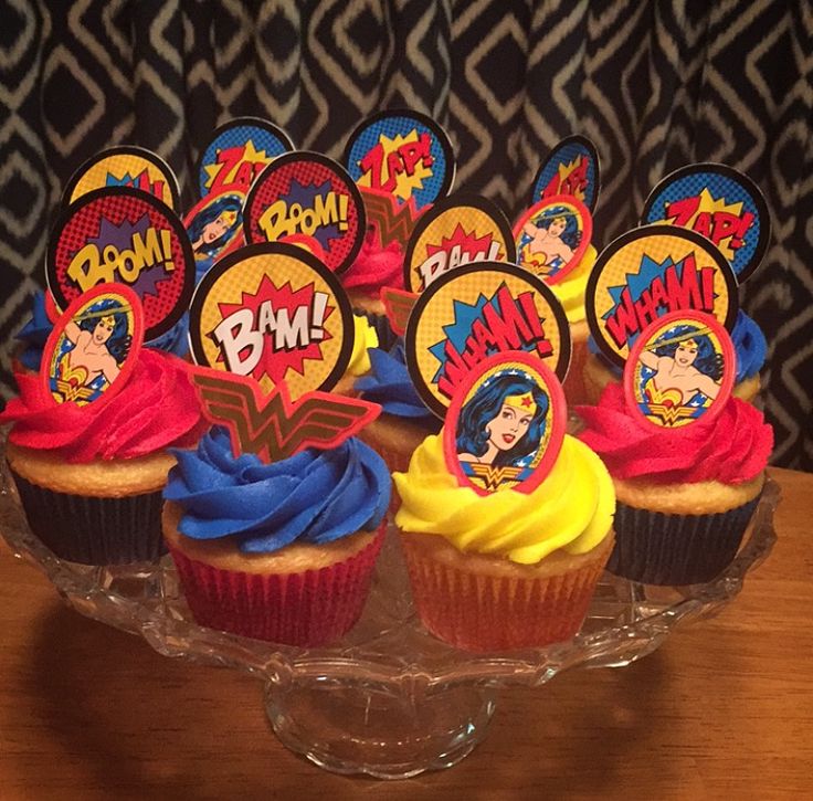 cupcakes decorated with comic characters on top of a glass plate, sitting on a table