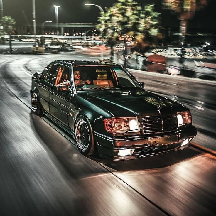 a black car driving down a street at night