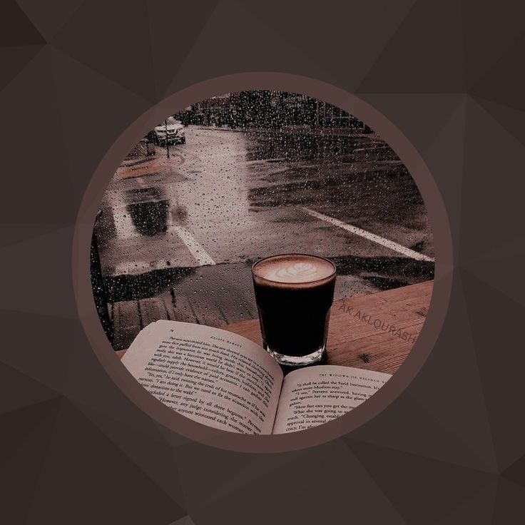 an open book and a cup of coffee on a wooden table in front of a rainy street