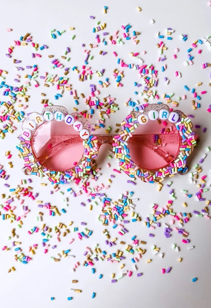 two pink sunglasses are surrounded by sprinkles