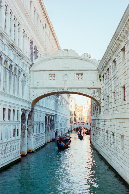 two boats are going under an overpass on a canal in venice, italy during the day