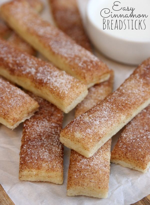 some sugary bread sticks are on a paper towel next to a small white bowl