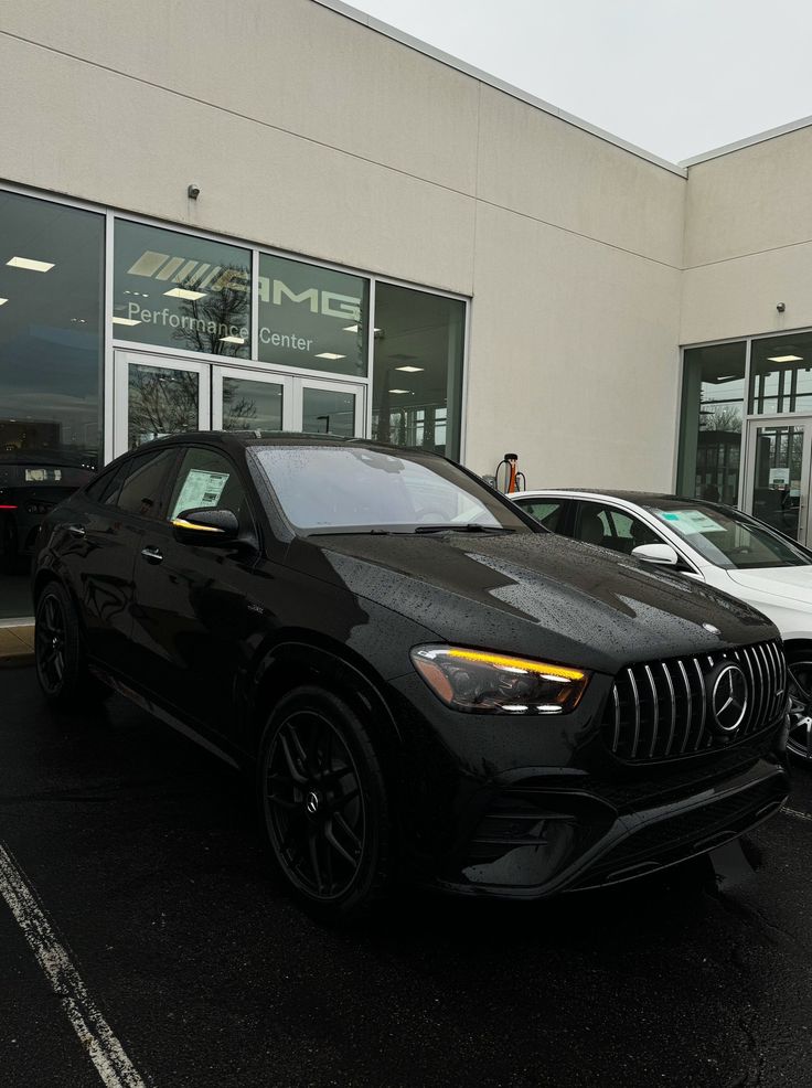 two cars parked in front of a mercedes dealership