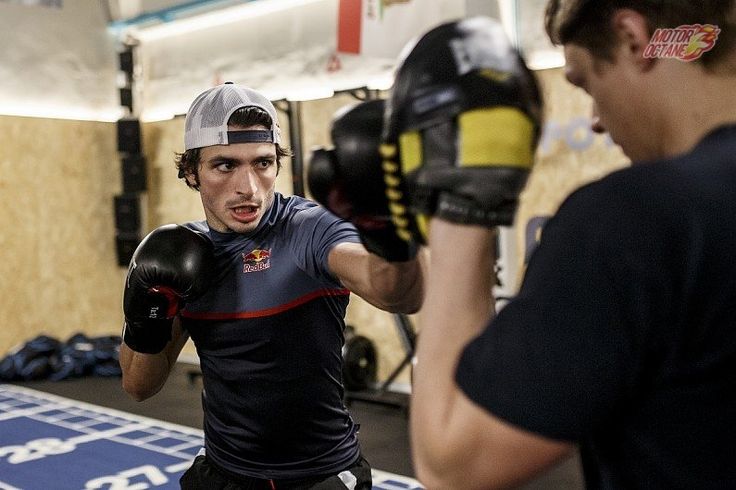 two young men practicing boxing with gloves on their hands and one man wearing a black t - shirt