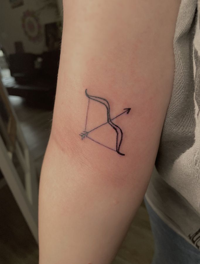 a person with a tattoo on their arm holding an arrow in the shape of a bow