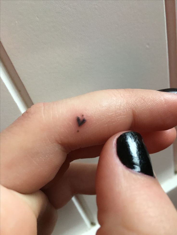 a woman's finger with a tiny black heart on it