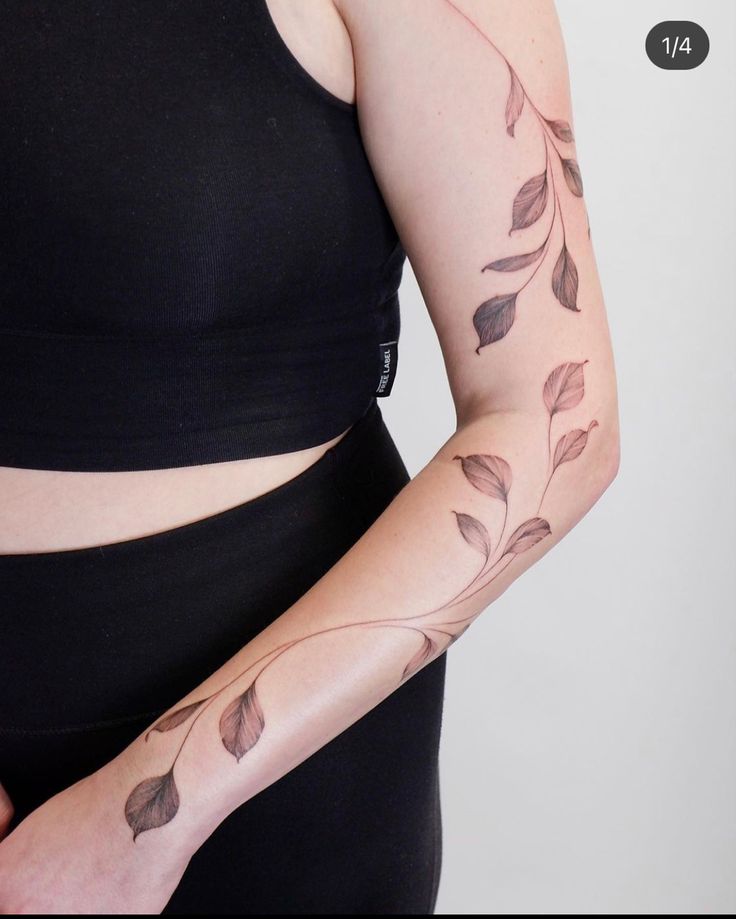 a woman's arm with leaves on it and a tattoo design on the arm