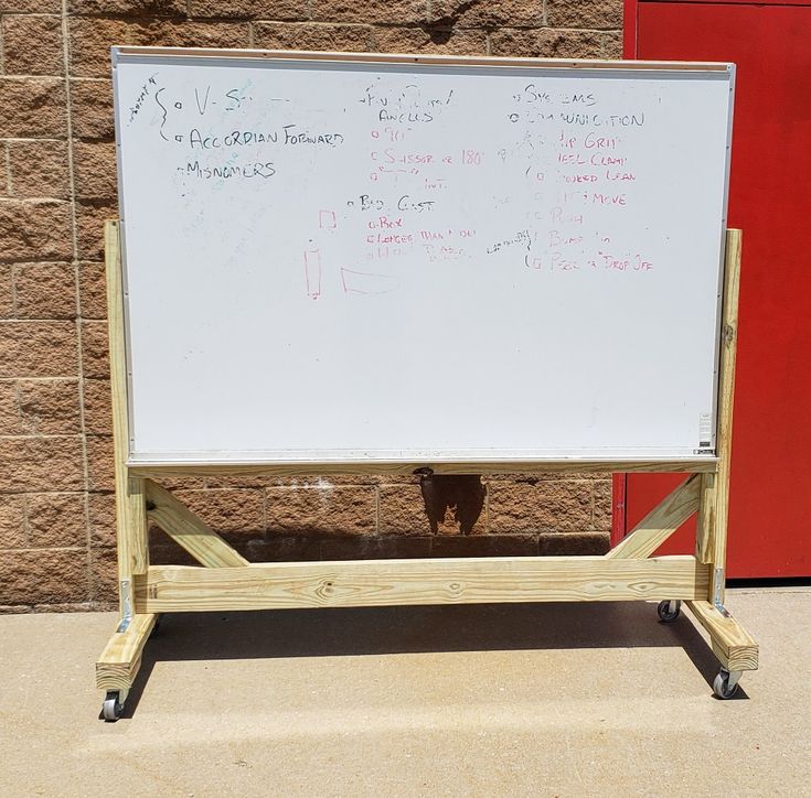 a white board with writing on it in front of a brick wall and red door