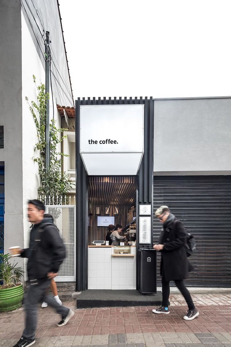 two men are walking past a coffee shop