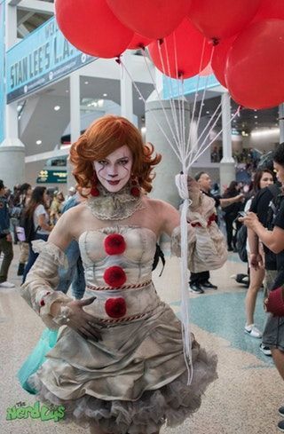 a woman dressed as penny the clown holding red balloons