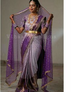 a woman in a purple and gold sari is posing for the camera with her hands on her hips