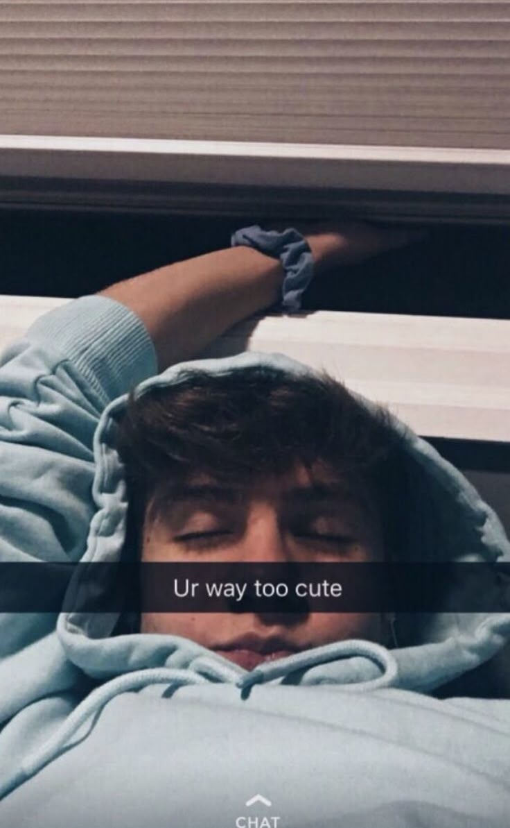 a man in a blue hoodie laying on top of a window sill with the words ur way too cute above his head